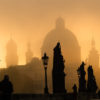 Silhouette of statue and tourists on Charles bridge during sunrise